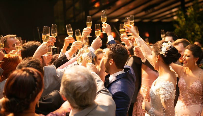 Elegantly dressed guests with champagne glasses toast together at a wedding reception inside Drugan’s Castle Mound in Holmen, WI.