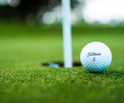 A Titleist golf ball sits close to the hole on the green at Drugan’s Castle Mound in Holmen, Wisconsin, with the flagstick behind.