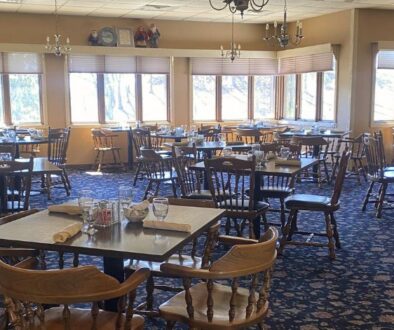 Drugan’s Castle Mound dining room with wooden chairs, set tables, and large windows filling the space with natural light.
