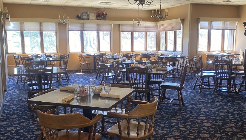 Drugan’s Castle Mound dining room with wooden chairs, set tables, and large windows filling the space with natural light.