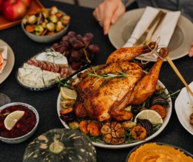 Holiday party guests enjoy roast chicken, sides, and wine at a festive table.